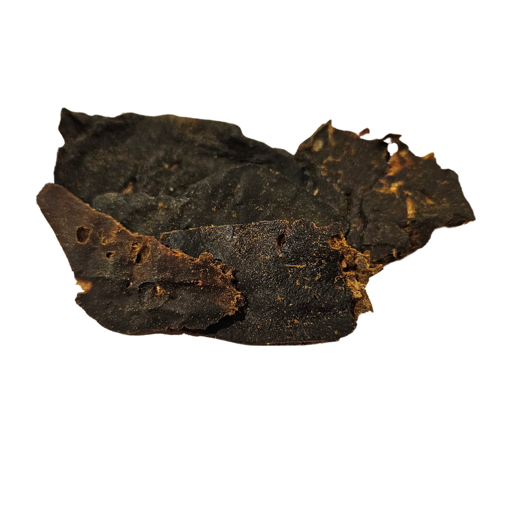 A piece of chicken liver, dried and blackened, intended as a pet treat.